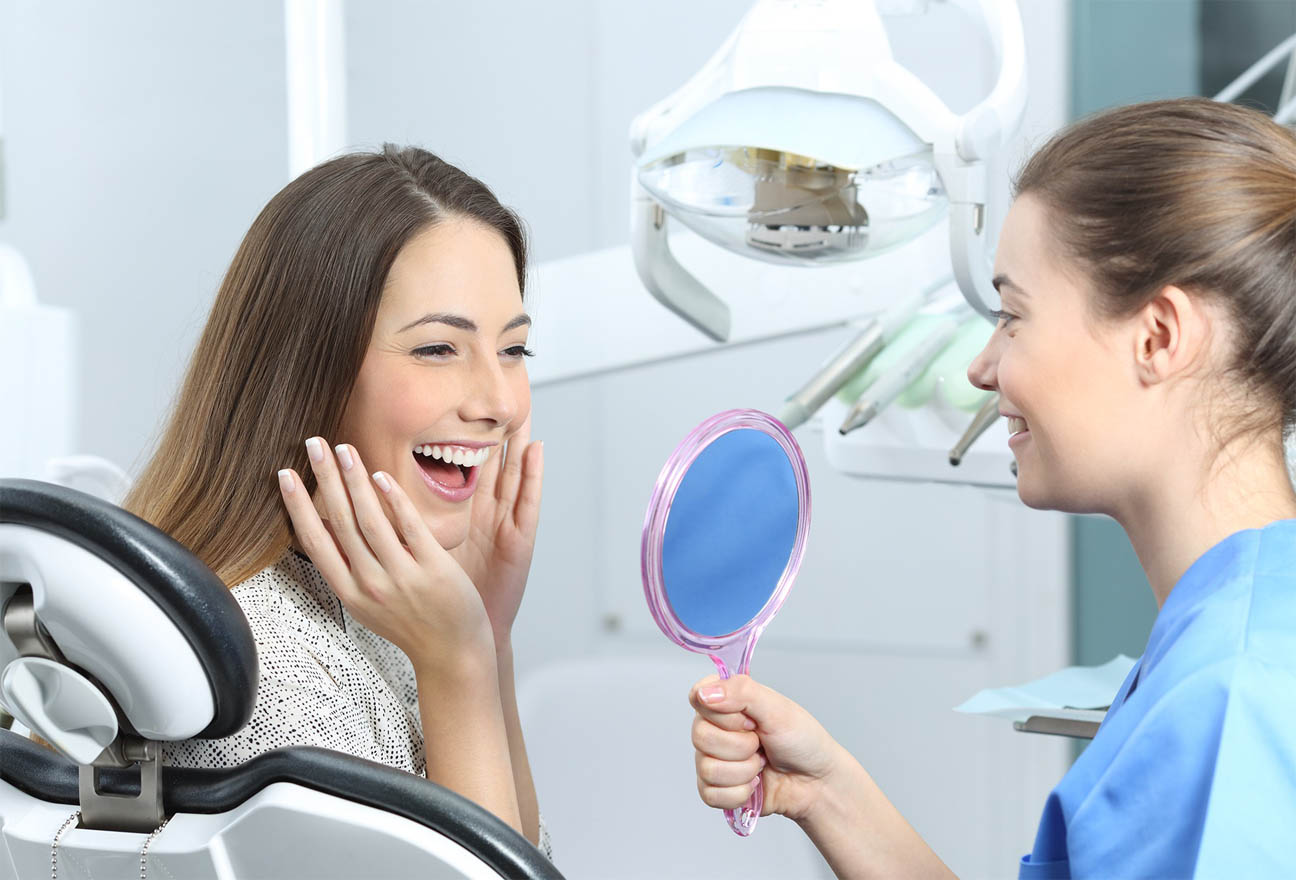 A dentist sitting chairside with smiling